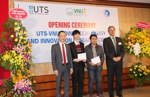 Four participants at the opening ceremony stand before the UTS–VNU Joint Technology and Innovation Research Centre banner.