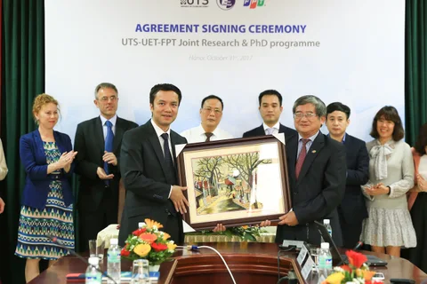 Delegates exchange a framed presentation at the UTS, VNU-UET and FPT ceremony.