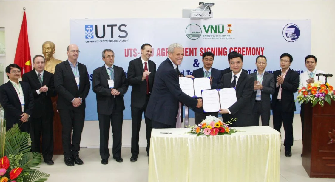 Delegates display a cooperation agreement in front of the UTS and VNU-UET signing banner.