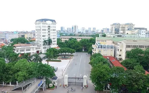 A tree-lined avenue and buildings at VNU University of Engineering and Technology.
