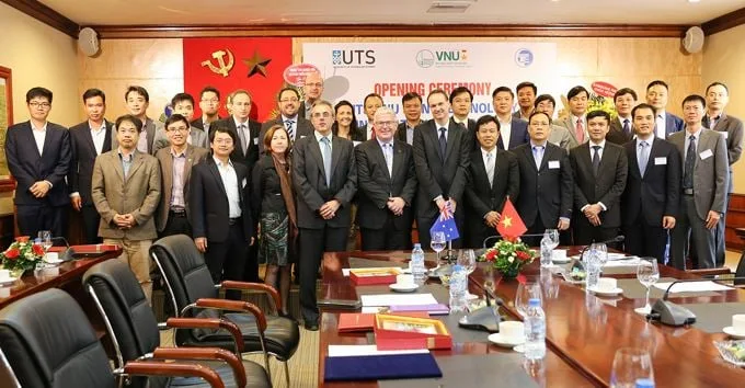 A large group poses in front of the centre opening banner and behind a conference table.